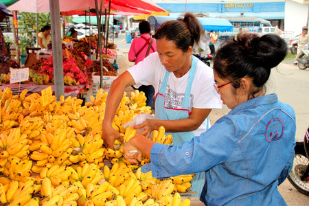 PAYAKKAPHUMPHISAI, MAHASARAKHAM - SEPTEMBER 2 : Street purchaser is buying Dainty bananas at local fruits market on September 2, 2015 in Payakkaphumphisai, Mahasarakham, Thailand.のeditorial素材
