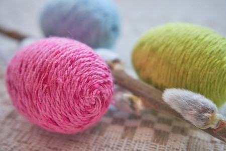 Colorful easter eggs and willow branch on a natural patterned linen tablecloth background. The...