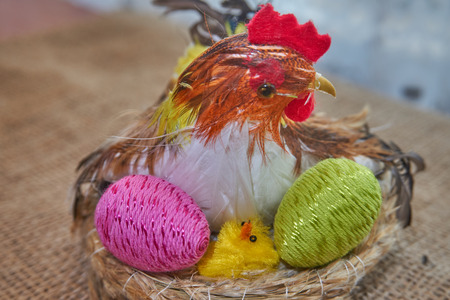 Happy Easter. Easter chick decoration in a nest hatches colorful easter eggs on a natural jute fabric background.の写真素材