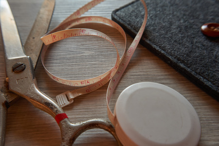 Old metal scissors and tailor measure tape on grey wooden background. Retro sewing accessories for home sewing and repair of clothing.の写真素材