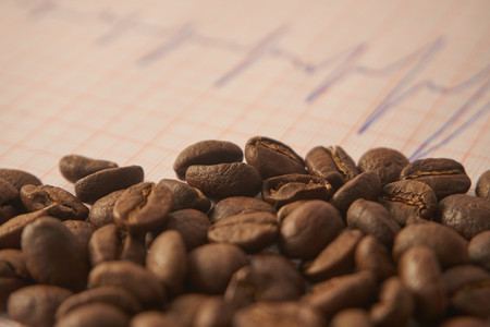 Loose roasted coffee beans on an ECG tracing showing an increased heart beat conceptual of coffee as a stimulant and its health implications,  low angle selective focusの写真素材