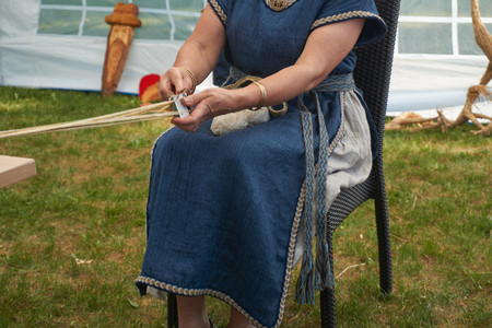 Woman in traditional clothing doing handicraft using natural thin cords in a close up cropped viewの写真素材