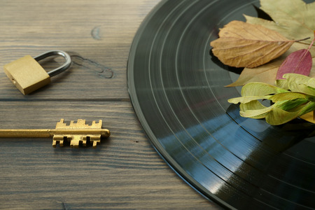 Brass padlock and golden key next to vintage vinyl record on rustic wood background access to audio files concept with free copy spaceの写真素材