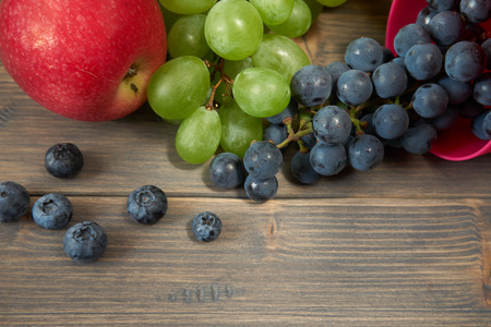 Mix of juicy summer fruits and berries. Pear, apple, green and blue grapes, blueberries on gray rustic wood background space for textの写真素材