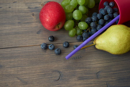 Mix of juicy summer fruits and berries. Pear, apple, green and blue grapes, blueberries on gray rustic wood background space for textの写真素材