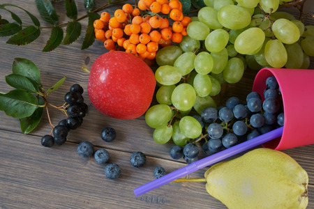 Mix of juicy summer fruits and berries. Pear, apple, green and blue grapes, blueberries, rowan and aronia on gray rustic wood background space for textの写真素材