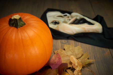 Orange pumpkin autumn leaves and halloween mask on old wood table with free copy spaceの写真素材