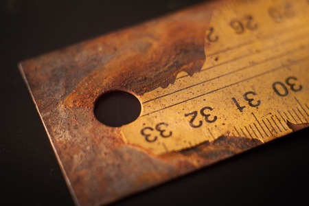 Old rusty metal ruler with numbered label cracking on black background surface with free copy spaceの写真素材