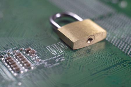 Brass lock sitting on electric circuit as concept of internet data security. Close-up full frame viewed from above with copy spaceの写真素材