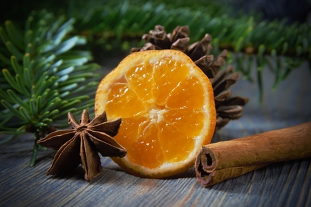 Piece of lemon, cinnamon and badian star anise next to pine branch and conifer cone, sitting on wooden table surface background with copy space. Mulled wine recipe conceptの写真素材