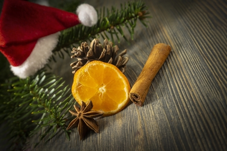 Piece of orange, cinnamon and badian star anise next to pine branch and red Santa hat, sitting on wooden table surface background with copy space. Christmas background, mulled wine recipe conceptの写真素材