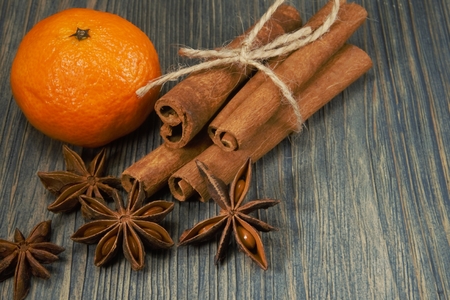 Bunch of cinnamon, orange and badian star anise next to pine branch, sitting on rustic wooden table surface backgroundの写真素材