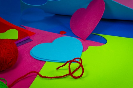 Colorful balls or red yarn and cardboard with heart shaped cut outs for handicrafts or scrapbooking....