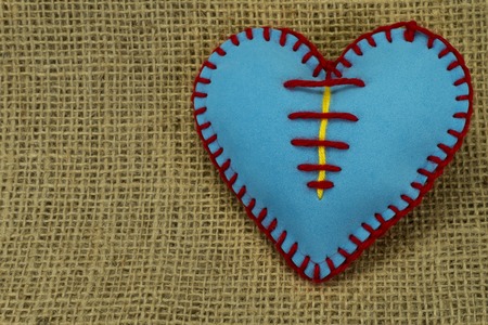 Valentine Day template, one handmade blue foam sheet stitched toy heart on jute canvas, close up, high angle view. Love, relationship, Valentines Day, broken heart and gay love conceptの写真素材