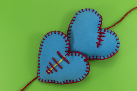 Heart shaped hand stitched textile hearts made of blue fabric and sewed with red threads on green chromakey background for romantic or Valentines conceptsの写真素材