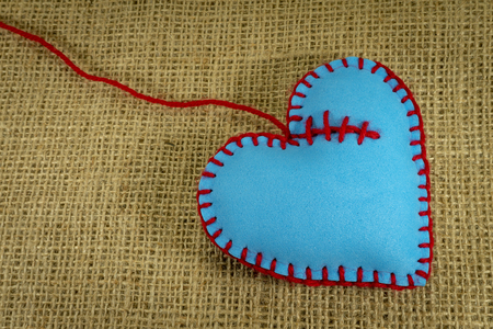 Valentine Day template, one handmade blue foam sheet stitched toy heart on jute canvas, close up, high angle view. Love, relationship, Valentines Day, broken heart conceptの写真素材