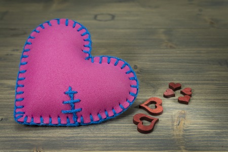 Heart shaped hand stitched textile heart and laser cut red wooden heart shapes on light wooden surface background for love and romance concepts with free copy space for textの写真素材