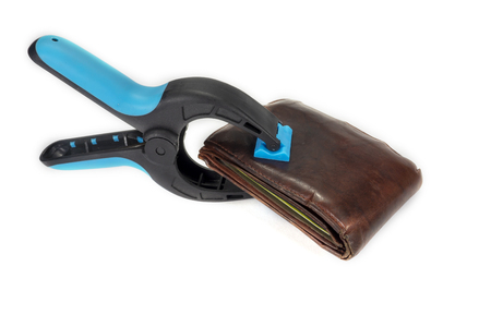 Old worn leather wallet held by an industrial clamp over a white background in a conceptual image of financial security or controlling spendingの写真素材