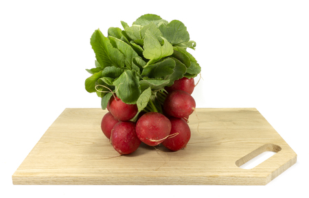 Bundle of fresh red radish with green leaves on a wooden cutting board isolated on a white backgroundの写真素材