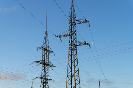 Two high voltage electric line poles viewed from low angle against clear blue sky, power energy in the cityの写真素材