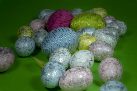 Handmade Easter eggs and yellow feathers in close-up on green background. Christian symbols of Palm Sunday or Easterの写真素材