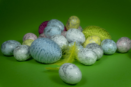 Handmade Easter eggs and yellow feathers in close-up on green background. Christian symbols of Palm Sunday or Easterの写真素材