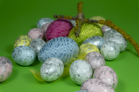 Handmade Easter eggs, feather and cross of twigs in close-up on green background. Christian symbols of Palm Sunday or Easterの写真素材
