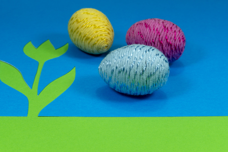 Willow buds and Easter eggs in close-up as a set of decoration on spring theme in Christianity, placed on green background with flower cutout of blue paperの写真素材