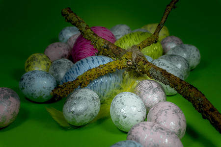 Handmade Easter eggs, feather and cross of twigs in close-up on green background. Christian symbols of Palm Sunday or Easterの写真素材
