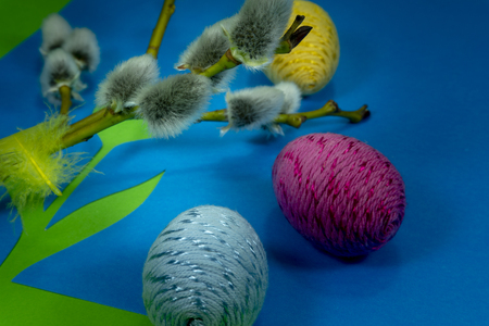 Willow buds, Easter eggs and feather in close-up as a set of decoration on spring theme in Christianity, placed on green background with flower cutout of blue paperの写真素材