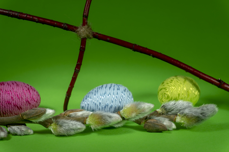 Handmade Easter eggs, soft willow buds and cross of twigs in close-up on green background. Christian symbols of Palm Sunday or Easterの写真素材