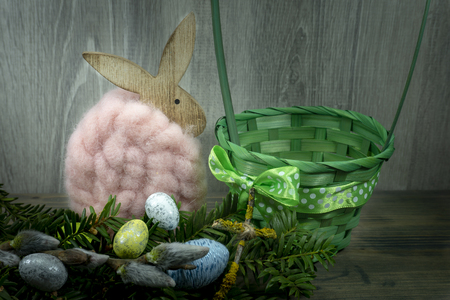 Easter still life or card design with cute little woolly rabbit decoration, fresh spring flower and foil wrapped Easter eggs with copy space for your holiday messageの写真素材