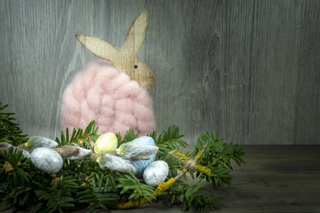 Easter still life or card design with cute little woolly rabbit decoration, fresh spring flower and foil wrapped Easter eggs with copy space for your holiday messageの写真素材