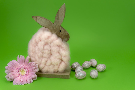 Colorful green Easter still life or card design with cute little woolly rabbit decoration, fresh spring flower and foil wrapped Easter eggs with copy space for your holiday messageの写真素材