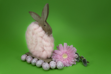 Colorful green Easter still life or card design with cute little woolly rabbit decoration, fresh spring flower and foil wrapped Easter eggs with copy space for your holiday messageの写真素材