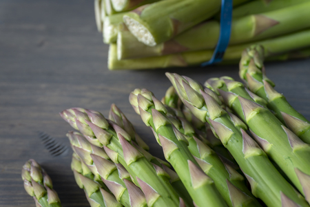 Bundle of fresh green asparagus on a rustic wooden table with copy space, selective focusの写真素材