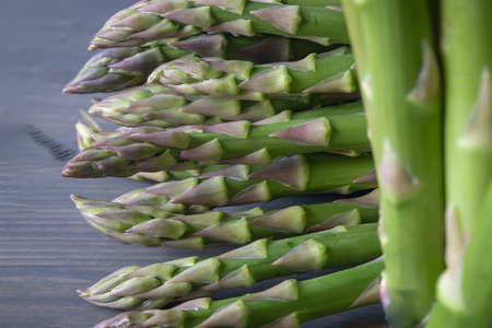 Bundle of fresh green asparagus on a rustic wooden table, selective focusの写真素材