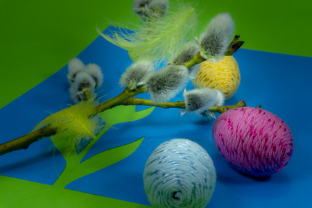 Willow buds, Easter eggs and feather in close-up as a set of decoration on spring theme in Christianity, placed on green background with flower cutout of blue paperの写真素材