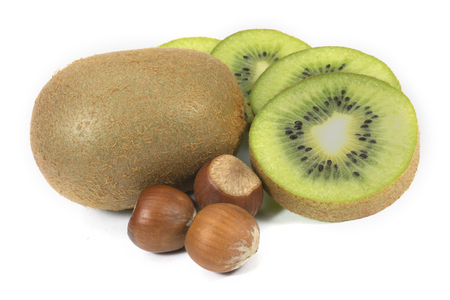 Whole and sliced kiwi fruit next to hazelnuts isolated on a white backgroundの写真素材