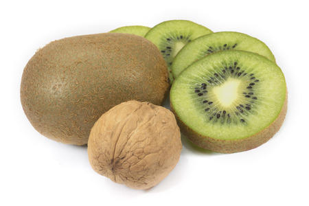 Whole and sliced kiwi fruit next to the walnuts isolated on a white backgroundの写真素材