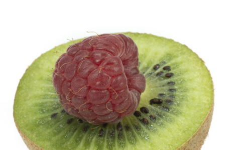 Red raspberry on green kiwi slice isolated on a white backgroundの写真素材