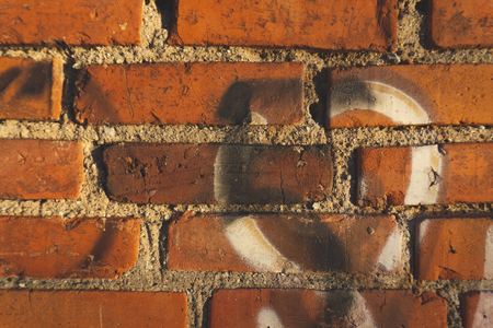 Old red brick wall with graffiti fragments, viewed in close-upの写真素材