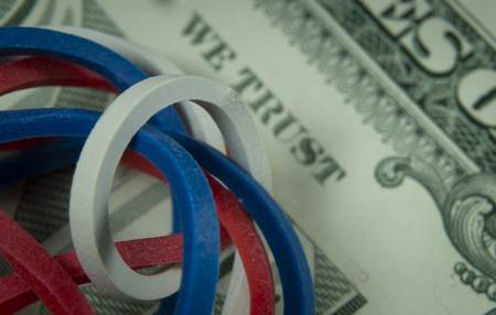 Twisted red, white and blue rubber bands on dollar banknote in a close up view, conceptual of trade, business, investment, savings, retirement, finance and moneyの写真素材