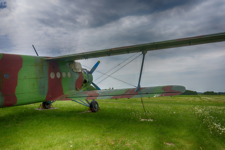 Vintage green biplane parked on exhibit in a lush green field viewed from the rear under a cloudy skyの写真素材
