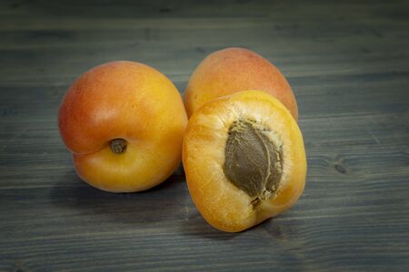 Fresh whole and sliced halved apricots on a rustic wooden table in a close up viewの写真素材