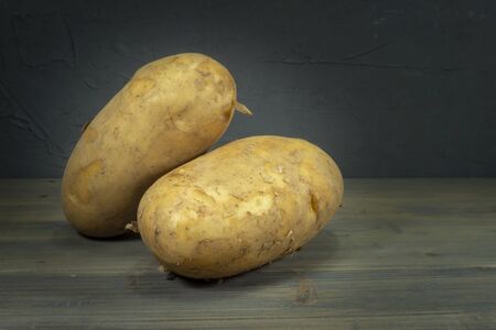 Fresh harvested potatoes on a rustic old wooden tabletop. Black wall in backgroundの写真素材