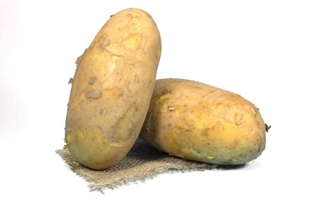 Raw, unwashed, unpeeled potatoes on a square of hessian isolated on whiteの写真素材