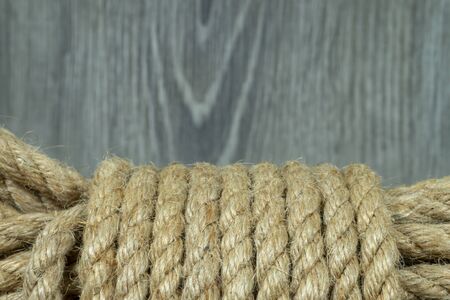 Twisted burlap jute twine rope in close-up on grey rustic background