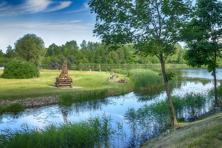 Tranquil lake with large ready built bonfire on the further shore waiting to be lit in the evening for a celebration or partyの写真素材
