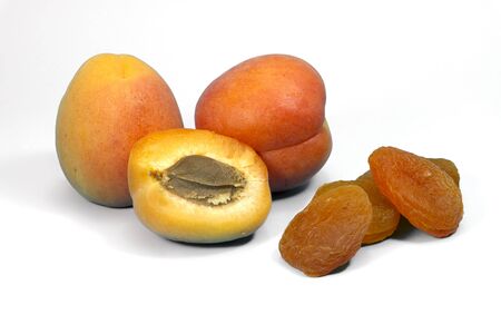 Dried apricots and fresh whole and sliced halved apricots in a close up view, isolated on whiteの写真素材
